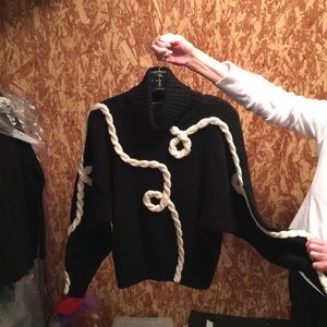 A black turtleneck sweater with white yarn details